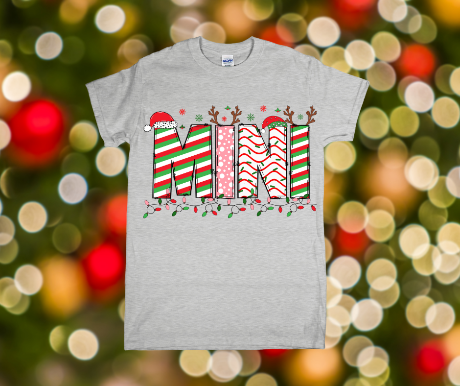 Gray t-shirt with Christmas-themed text design on a blurred festive background