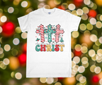 White t-shirt with Christmas-themed design featuring crosses and text on a blurred festive background.