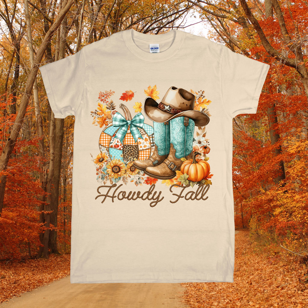 T-shirt with autumn-themed design featuring boots, a hat, and pumpkins against a forest background.