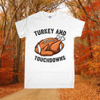 White t-shirt with 'Turkey and Touchdowns' design in an autumn forest setting