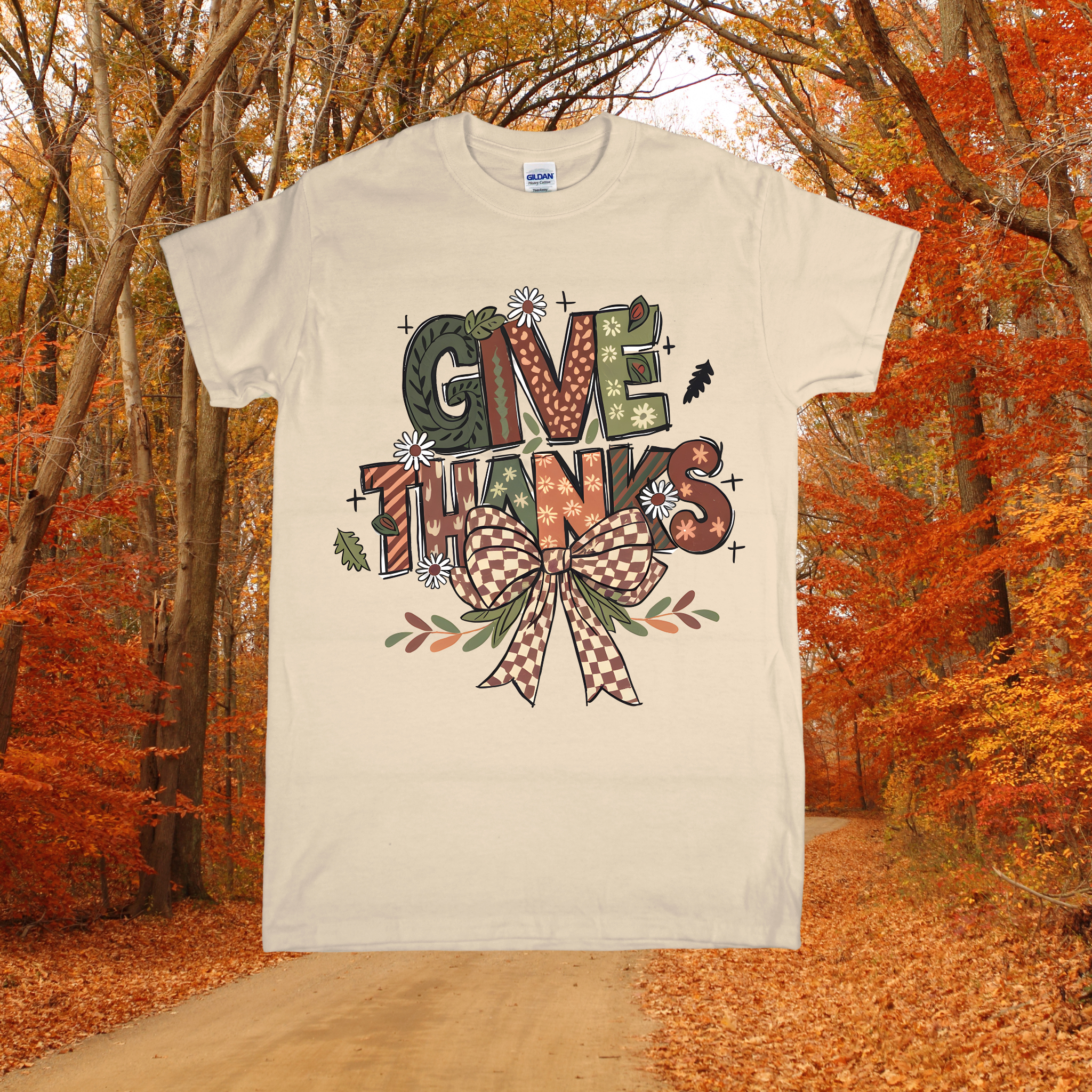 Beige t-shirt with 'Give Thanks' design in an autumn forest setting