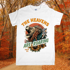 White t-shirt with a graphic design of a lion and sunflower, text 'The Heavens Are Roaring', and Psalm 19:1 reference, set against an autumn forest background.