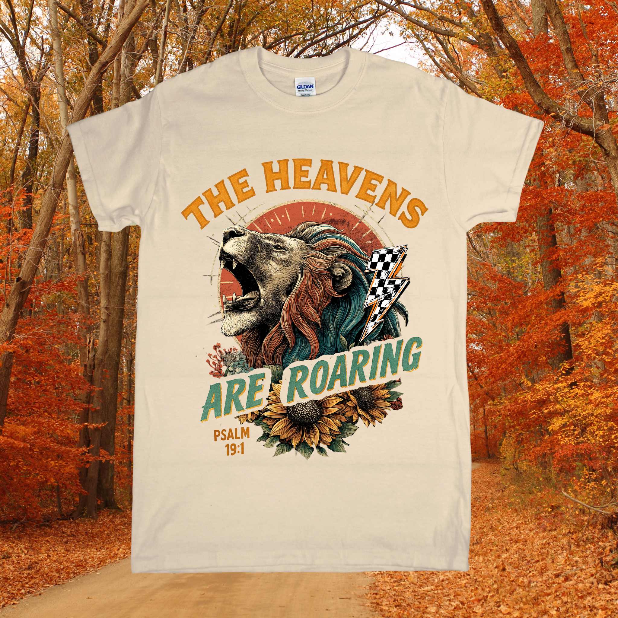 T-shirt with a lion graphic and text 'The Heavens Are Roaring' in an autumn setting