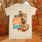 T-shirt with a lion and pumpkin design and 'Jesus has my back' text, set against an autumn forest background.