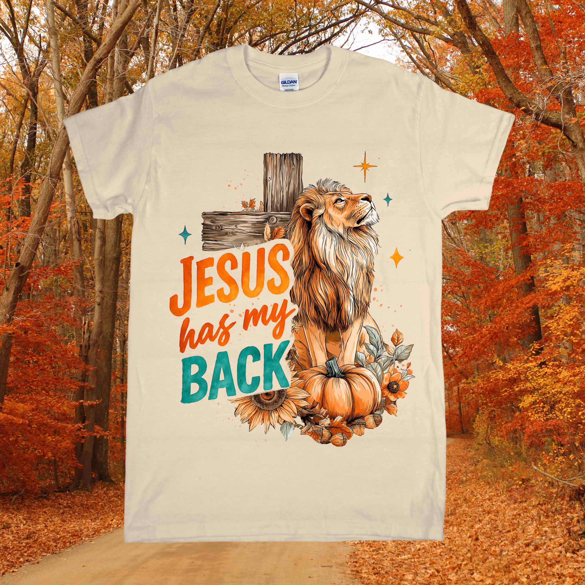 T-shirt with a lion and pumpkin design and 'Jesus has my back' text, set against an autumn forest background.